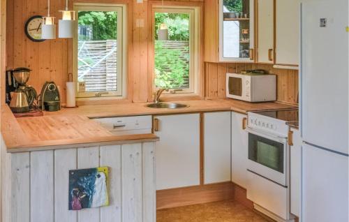 - une cuisine avec des placards en bois et un réfrigérateur blanc dans l'établissement Stunning Home In Gilleleje With 4 Bedrooms, Sauna And Wifi, à Gilleleje