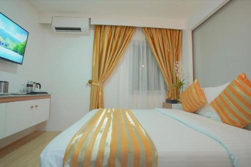 1 dormitorio con 1 cama grande y cortina de color naranja en Ragazzi Resort Hotel, en Naga