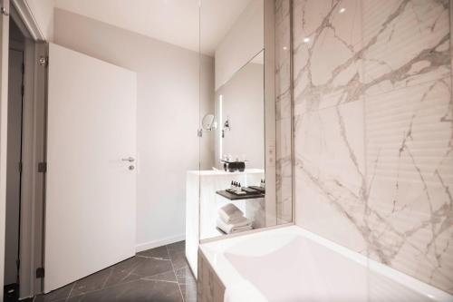 a white bathroom with a tub and a shower at Boutique Hotel Sablon in Bruges