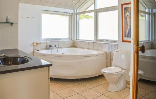 a bathroom with a tub and a toilet and a sink at Cozy Home In Harbore With House A Panoramic View in Harboør