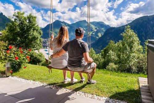 a man and a woman sitting on a swing at Chalet Familial Le Whymper 5 étoiles SPA Sauna Chatel in Châtel