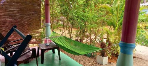 a hammock on a patio with a chair and trees at Elena Garden Resort and Restaurant in Trincomalee