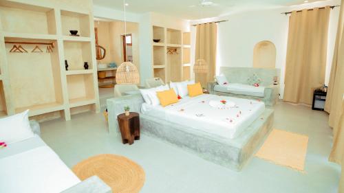 a large room with a bed and two chairs at Mnana Beach Bungalows in Michamvi