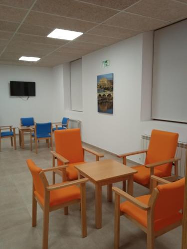 una stanza con sedie arancioni, tavolo e schermo di Albergue de Maella a Maella