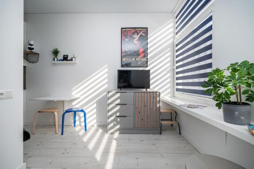 een woonkamer met een tv en een bureau met stoelen bij Studios K1A in Vilnius