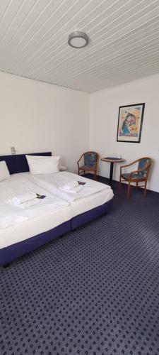 a bedroom with a bed with two chairs and a table at Aparthotel Höper in Oyten