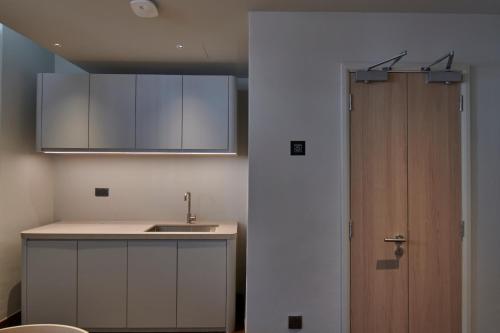 a kitchen with a sink and a wooden door at KINN Studios in Singapore