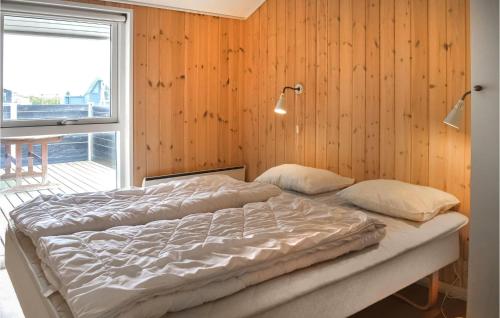 two beds in a room with wood walls and a window at Frk, Lyng in Harboør