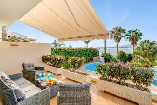 eine Terrasse mit Stühlen, einem Tisch und einem Pool in der Unterkunft Beach Front Villa Mer Blu by Ezoria Villas in Coral Bay