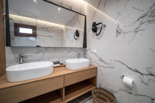 uma casa de banho branca com um lavatório e um espelho em Avli Guest House em Tympáki