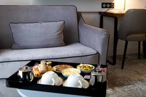 a tray of food on a table next to a couch at Le Grand Hôtel Grenoble, BW Premier Collection by Best Western in Grenoble