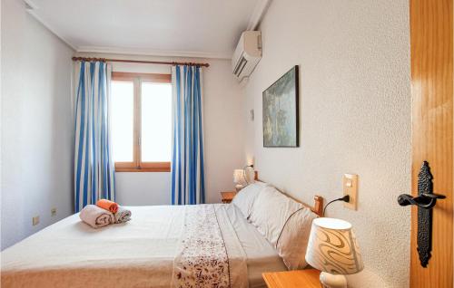 トレビエハにあるStunning Apartment In Torrevieja With 2 Bedrooms, Wifi And Outdoor Swimming Poolのベッドルーム1室(青いカーテン、窓付)