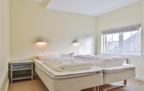 a white room with two beds and a window at Klitten in Søndervig