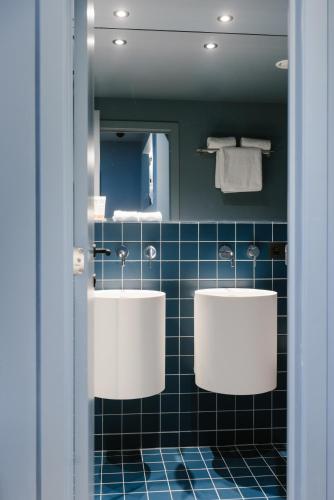 two sinks in a bathroom with blue tiles at Maison Arya in Brussels