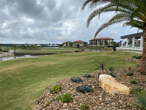 a golf course with a palm tree and a green at Resort One Bedroom Apartment in Pelican Waters