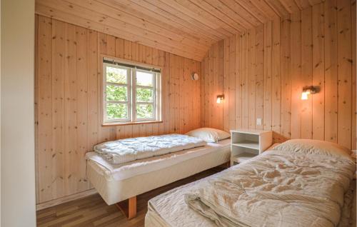 Nice Home In Hemmet With 2 Bedrooms And Wifi في Falen: سريرين في غرفة بجدران خشبية ونافذة