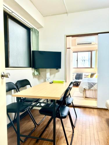 a room with a table with chairs and a tv at Hotel KinRin in Tokyo