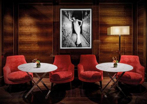 a room with red chairs and two tables and a picture at Bvlgari Hotel Paris in Paris