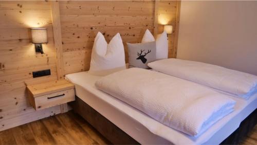 Schlafzimmer mit einem Bett mit weißer Bettwäsche und Kissen in der Unterkunft Bucherwirt Appartements in Buch bei Jenbach