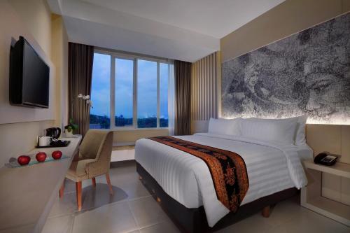 a bedroom with a large bed and a large window at Aston Banyuwangi Hotel and Conference Center in Banyuwangi