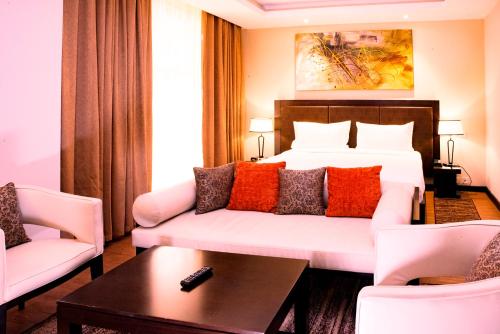 a hotel room with a bed and a couch and chairs at DoubleTree by Hilton Nairobi in Nairobi