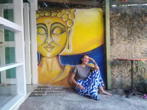Una donna seduta davanti a un grande dipinto di Chania Hostel Youth a Chania