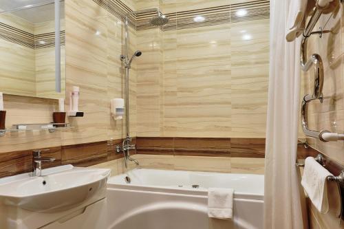 La salle de bains est pourvue d'une baignoire, d'un lavabo et d'une baignoire. dans l'établissement Intourist Hotel, à Novgorod