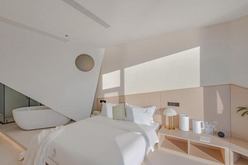a bedroom with a white bed and a white wall at Dali Oriental Seaview Hotel -Dali Erhai in Dali