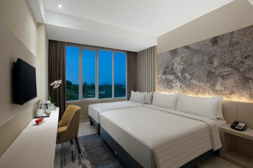 a hotel room with a large bed and a window at Aston Banyuwangi Hotel and Conference Center in Banyuwangi