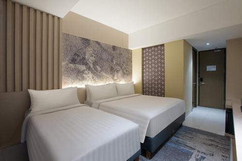 two beds in a hotel room with at Aston Banyuwangi Hotel and Conference Center in Banyuwangi