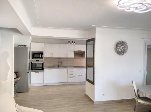 une cuisine avec des armoires blanches et une table dans une pièce dans l'établissement Residence les Etoiles, à Juan-les-Pins