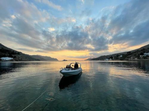 a small boat in the water at sunset at Symi . VILLA CALME (Sur la Mer). in Symi