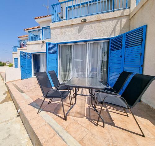 eine Terrasse mit einem Tisch und Stühlen vor einem Gebäude in der Unterkunft Beach Vibes Apartment in Pyla