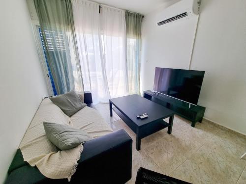 a living room with a couch and a tv and a table at Beach Vibes Beachfront Apartment in Pyla