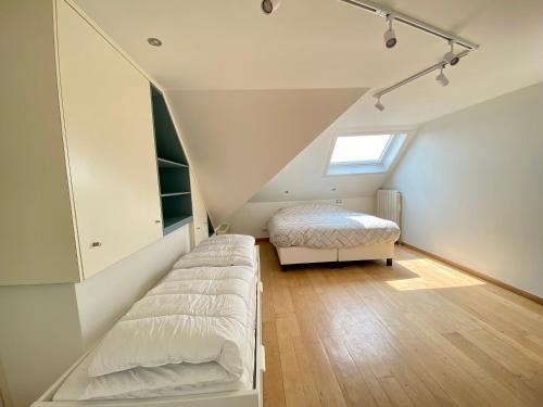sypialnia na poddaszu z 2 łóżkami i oknem w obiekcie Vakantieappartement 'Golf Azur' w mieście Middelkerke