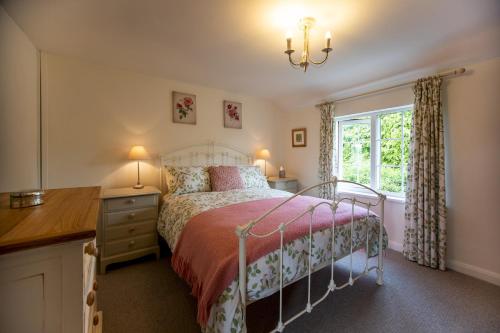 a bedroom with a bed and a desk and a window at 2 bed garden cottage nestled on the edge of Exmoor in Bishops Nympton