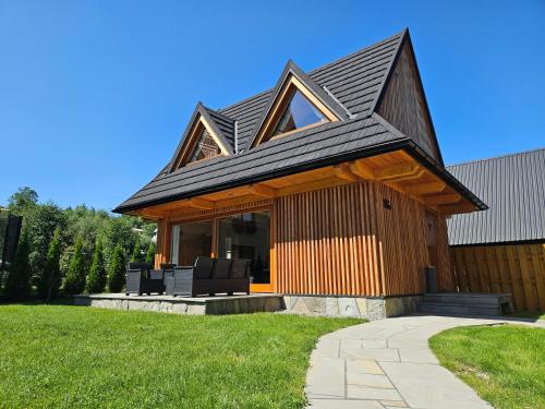 una casa con techo de gambrel en un césped en Górska Baja Premium House, en Witów