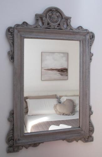 a mirror hanging on a wall with a bed at Residenza Porta Perlici Assisi Apartment in Assisi