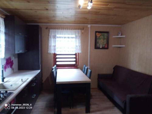 a kitchen with a table and a couch in a room at Ostoja Jarząbka in Wąsewo