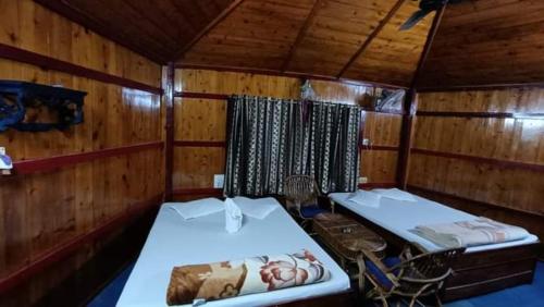 Habitación con 2 camas en una cabaña de madera en Akarshan Bono Bunglow, en Lataguri