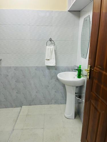 ein Badezimmer mit einem weißen Waschbecken und einem Spiegel in der Unterkunft Idyllic Sojourn in Nakuru