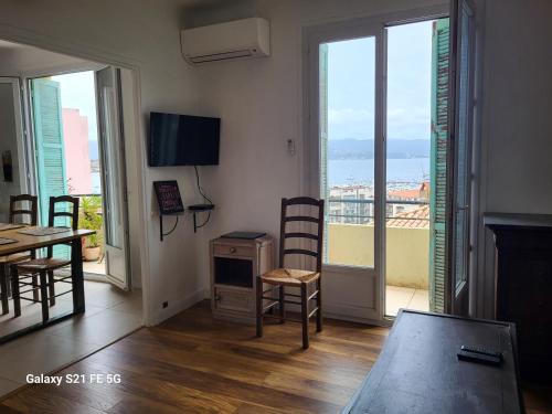 un salon avec une table, des chaises et des fenêtres dans l'établissement T3 Ajaccio vue mer, à Ajaccio