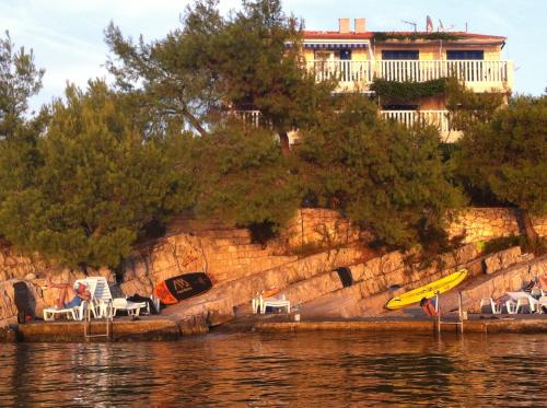 a group of chairs and a yellow kayak on the water at Sunset Villa Hvar in Hvar