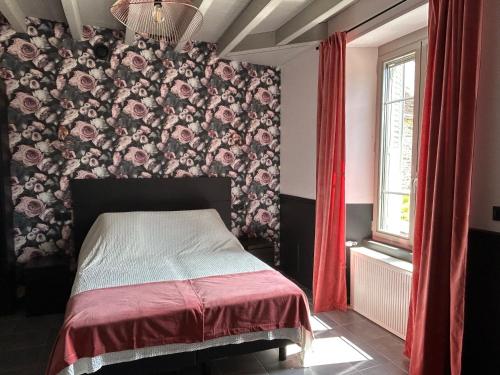 1 dormitorio con 1 cama con pared de flores en Gite La Fileuse, en Saint-Plantaire