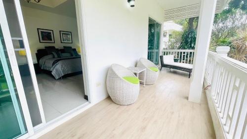 a room with two white chairs and a bed at Baan Ing Khao in Pak Chong
