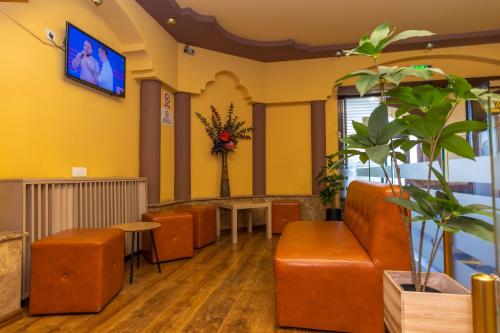 een wachtkamer met oranje meubels en een tv aan de muur bij Hotel Sir Gara de Nord in Boekarest