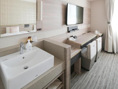a bathroom with a white sink and a mirror at Vessel Inn Shigamoriyama Station in Moriyama