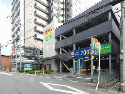 a building with a parking lot in front of it at Vessel Inn Shigamoriyama Station in Moriyama