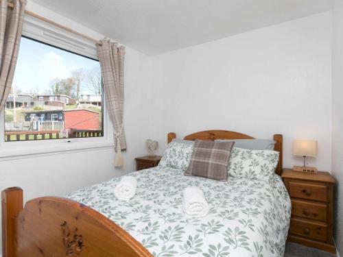 Schlafzimmer mit einem Bett und einem Fenster in der Unterkunft Pass the Keys Comfortable 2 Bed Riverside Chalet near Snowdonia in Caernarfon