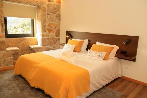 a bedroom with a large bed with an orange blanket at Casa Da Belina : casa de ferias com piscina, Labruja, Ponte de Lima in Ponte de Lima
